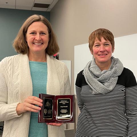 Amy Powell holds OER Award Plaque with Dean Kristi Palmer