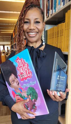 Dr Jobe holding her book "Tina Tucker Toodles" and her award